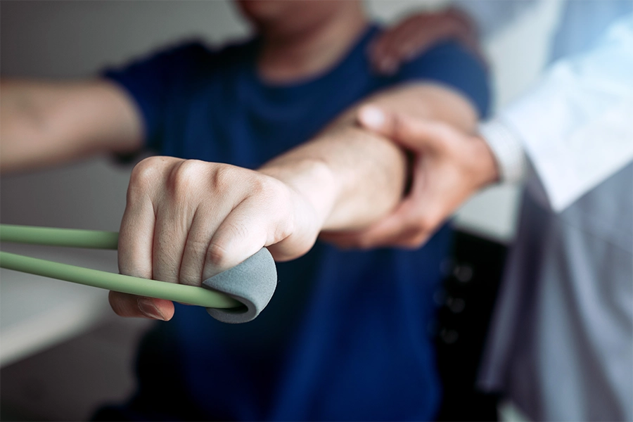 Oberkörper eines Physiotherapeuten, der einen Patienten beim Üben unterstützt