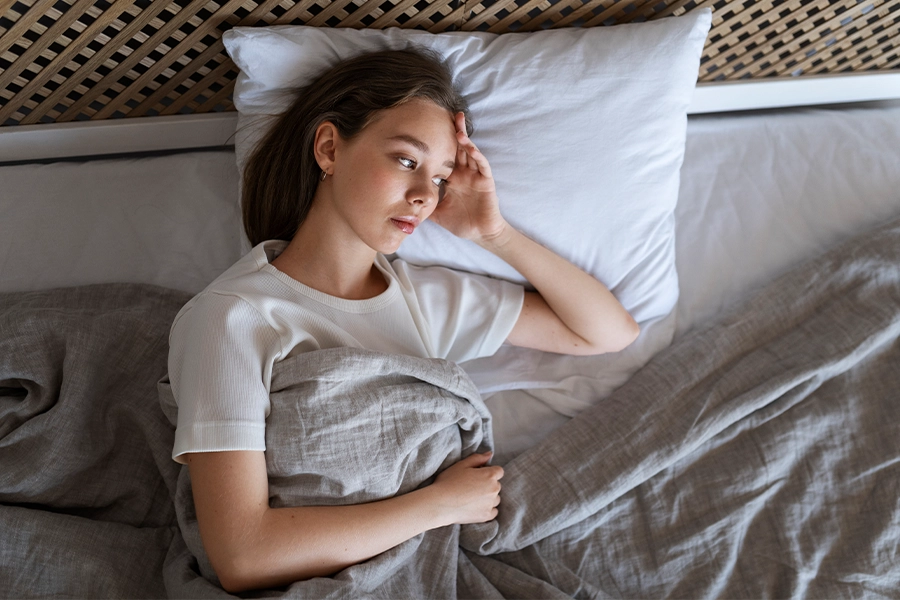 Blick von oben auf eine müde Frau, die im Bett liegt